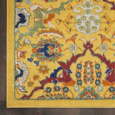 a yellow area rug with an ornate design on the top and bottom, sitting on a wooden floor