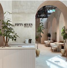 the interior of a modern restaurant with tables and plants in vases on the counter