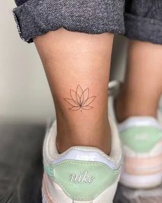 a woman's foot with a small flower tattoo on her left ankle and the word nuke written below it