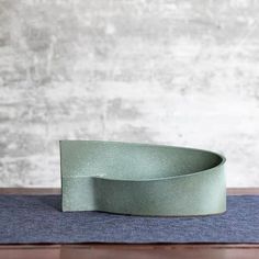 a green bowl sitting on top of a blue mat next to a wooden tablecloth