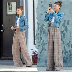 two women in plaid pants taking pictures with their cell phones