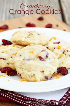 some cookies are on a white plate with cranberries and oranges around them