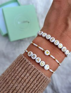 three bracelets with letters on them sitting next to a box