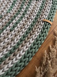 a close up of a rug on a wooden floor with dried grass in the foreground