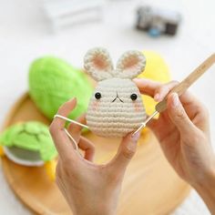 a person is holding up a small crocheted bunny ornament on a plate