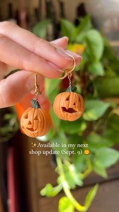 a person holding two pumpkin earrings in their hand