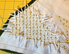 two pieces of white fabric sitting on top of a cutting board next to a ruler