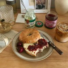 a bagel on a plate with cherries and jam