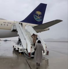 people boarding an airplane on the tarmac with stairs leading up to it's door