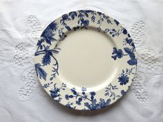 an empty blue and white plate on a lace doily