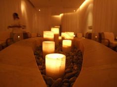 several lit candles in a room with rocks and pebbles