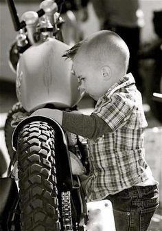 a small child is touching the tire of a motorcycle while standing on it's side