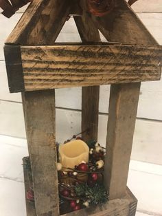 a wooden lantern with candles and berries on it