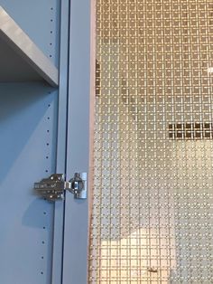 a close up of a metal door with a mesh curtain behind it and a key on the lock