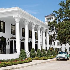 an old car is parked in front of a large white building with columns and pillars