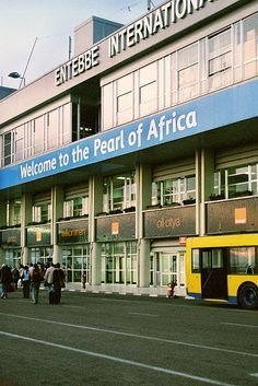 people walking in front of a building with a yellow and blue bus on the street