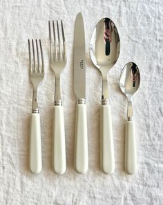 five forks, two spoons and one knife on a white cloth