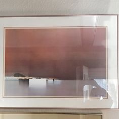 a framed photograph hanging on the wall next to a mirror with a chair in it