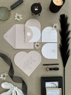 the wedding stationery is laid out on the table with flowers, feathers and other items