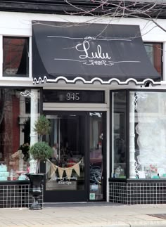 a store front with black awnings and white trim on the windows, decorated with decorations