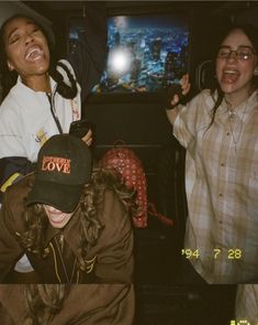 three young women laughing and standing in front of a television