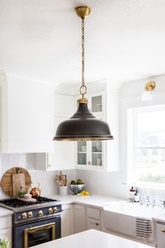 a kitchen with white cabinets and an island in the middle is lit by a black pendant light