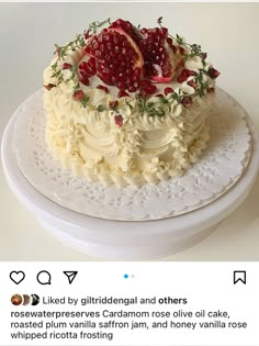 a cake with white frosting and pomegranates on top, sitting on a plate