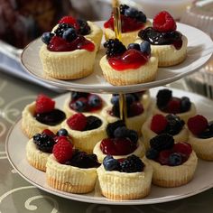 three tiered trays filled with cupcakes covered in fruit