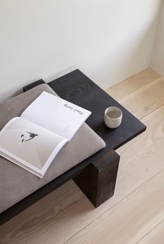 a coffee cup sitting on top of a table next to an open book and magazine