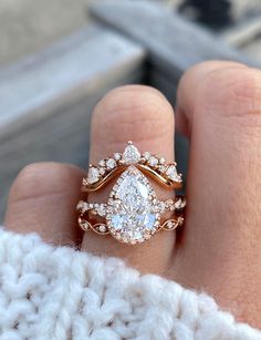 a woman's hand with a gold ring and two diamond engagement rings on it