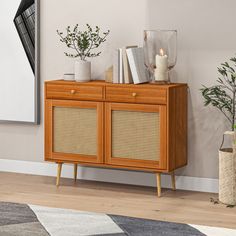 a wooden cabinet with wicker doors and two plants on top in a living room