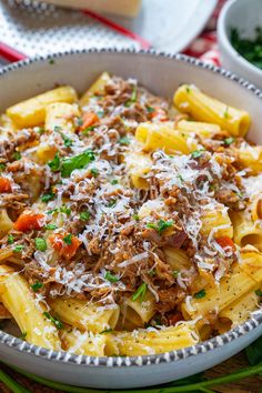 a bowl filled with pasta and meat covered in parmesan cheese