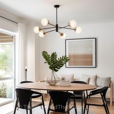 a dining room table with four chairs and a potted plant in the center, next to a couch