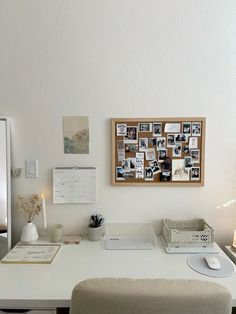 a white desk topped with a laptop computer next to a lamp and pictures on the wall