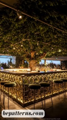 an outdoor bar is lit up at night with lights on the tables and stools