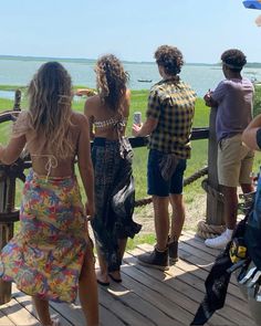 several people standing on a wooden deck looking out at the water