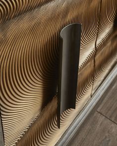 a close up of a metal door handle on a wooden surface with wavy lines in the background