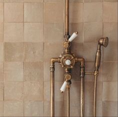 two faucets are attached to the side of a wall with pipes and hoses