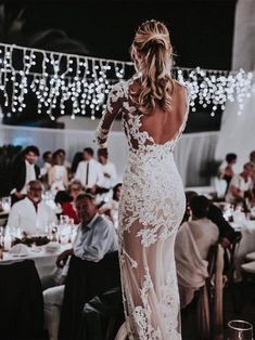 the back of a woman in a wedding dress at a dinner table with many people