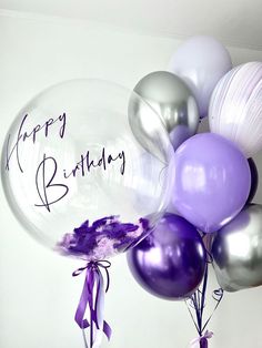 a bunch of balloons with the words happy birthday written on them and purple ribbons tied to each balloon