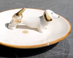 a dog figurine sitting on top of a white and brown plate with gold trim