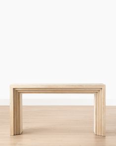 a wooden bench sitting on top of a hard wood floor next to a white wall