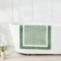 a bath tub with a green rug on it