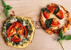 two small pizzas with tomatoes and spinach on them sitting on a cutting board