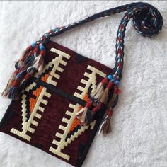 a small purse with tassels on it laying on top of a white blanket