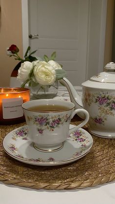 there is a tea cup and saucer set on the table with flowers in it