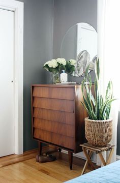 a wooden dresser sitting next to a mirror on top of a hard wood flooring