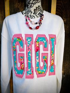 a white long sleeve shirt with the word gingh printed on it and a flowered necklace