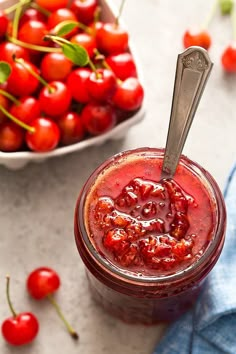 a jar filled with cherries next to a bowl of cherries