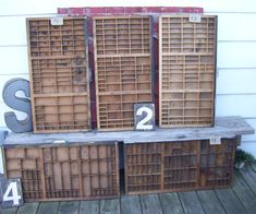 three wooden crates sitting on top of a wooden floor next to numbers and letters in front of a white house